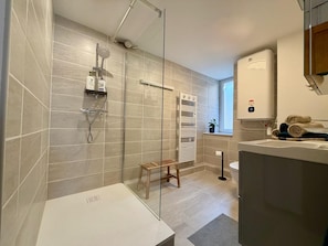 A modern bathroom with a glass shower enclosure, a white sink, and a towel rack.