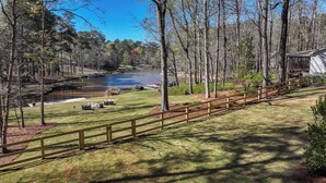 A lakeside view with a wooden deck, a boat dock, and a building in the background.