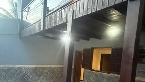 A spacious indoor area with a tiled floor, a wooden balcony, and a reception desk. - MARINAS DUPLEX HOUSE (Marinas Angra dos Reis)