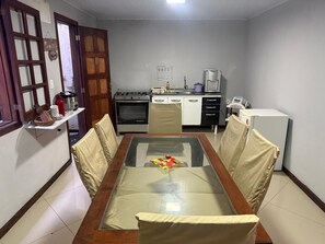 Cozy dining area with a glass-top table and four chairs, adjacent to a fully equipped kitchen.