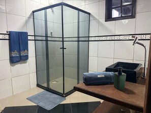 Enjoy a refreshing shower in this bathroom featuring a glass-enclosed shower area, a towel rack, and a bath mat.
