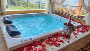 A hot tub with rose petals and champagne, overlooking a scenic landscape. - Aldeia Manacás Pousada Conceito (São Bento do Sapucaí)