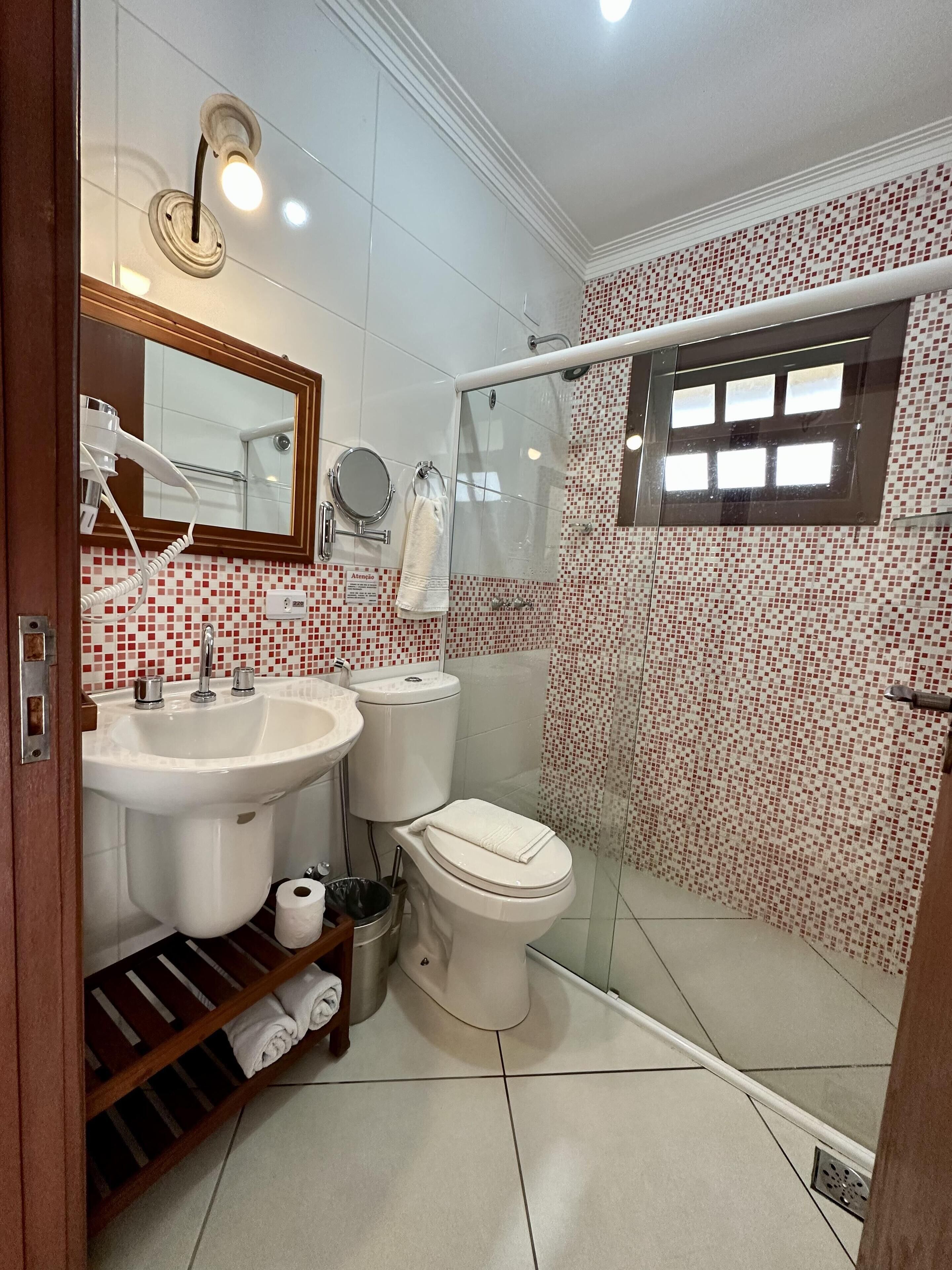 A bathroom with a shower, toilet, sink, and a mirror.
