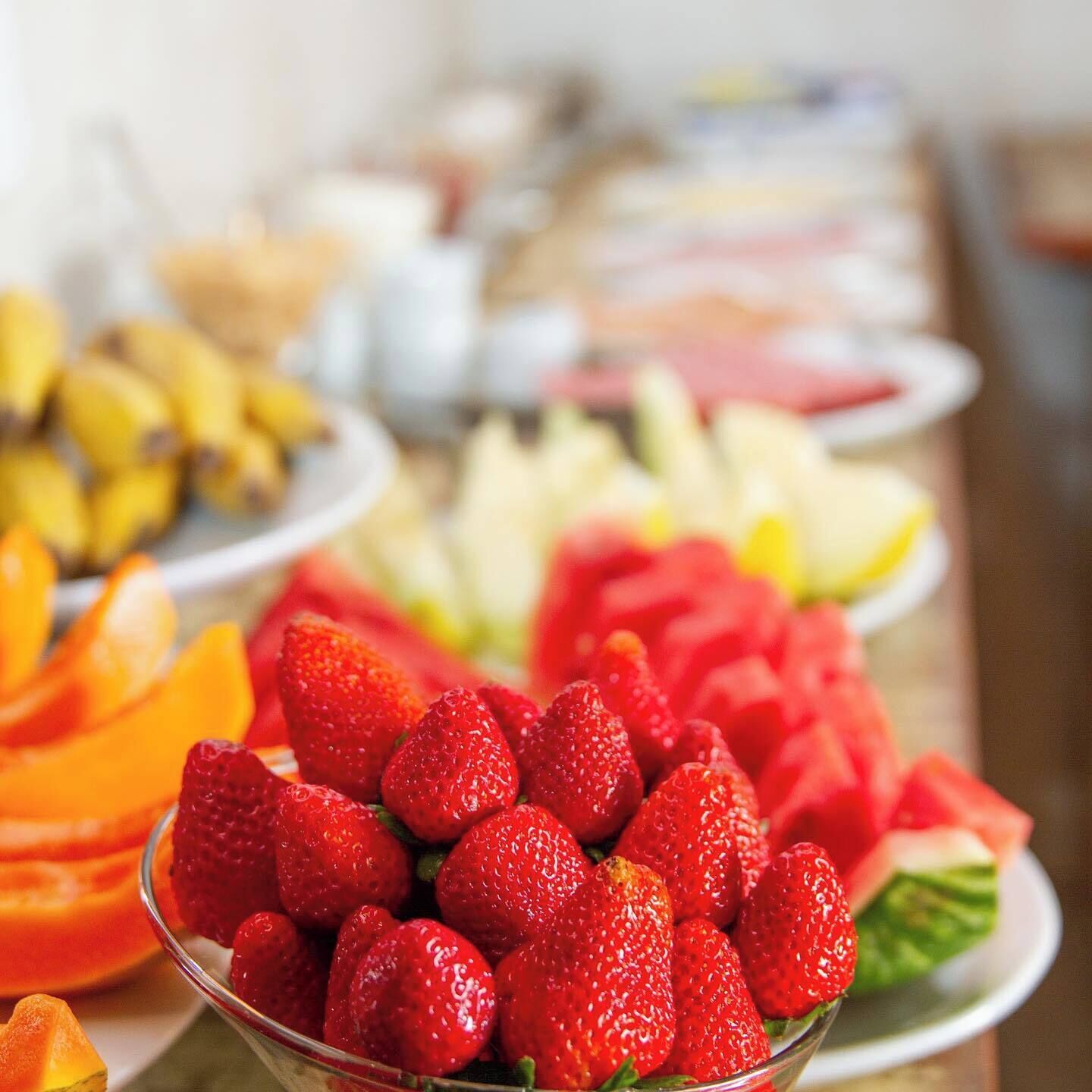 A buffet with various fruits including strawberries, watermelon, and mangoes.