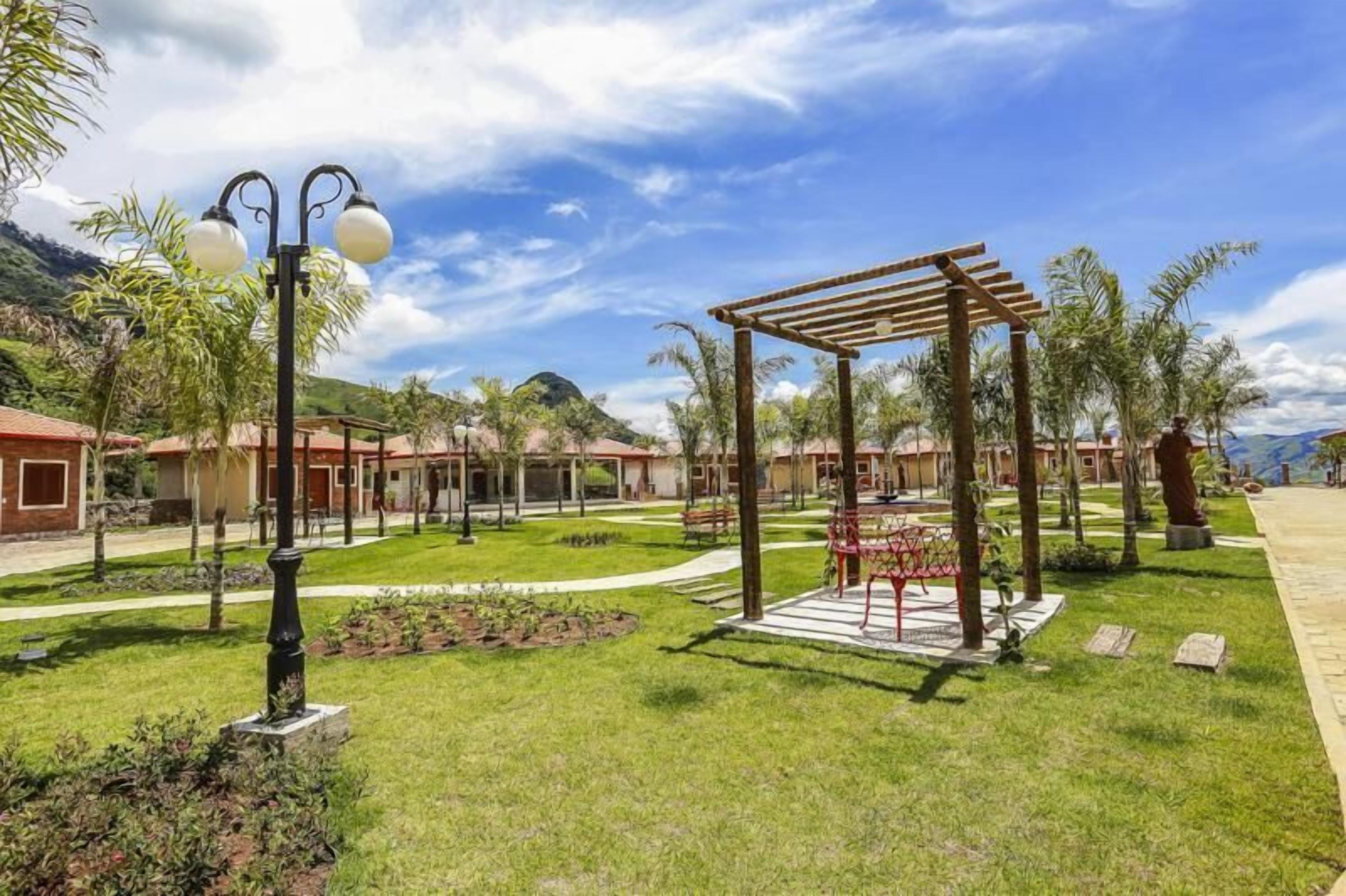 Un patio con una pérgola, bancos y un farol.