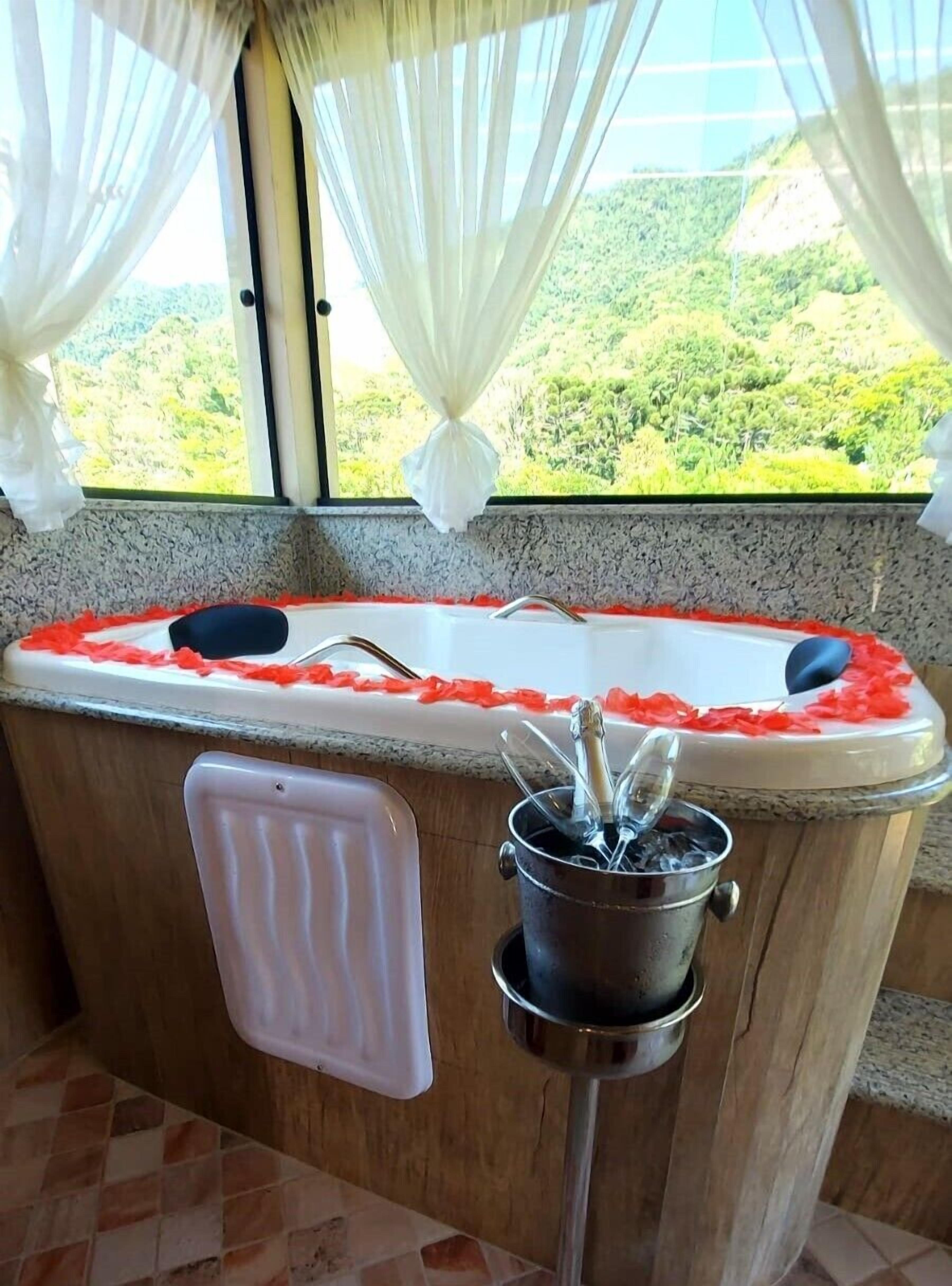 Ein Badezimmer mit einer Badewanne, einem Handtuchhalter und einem Fenster mit Vorhängen.