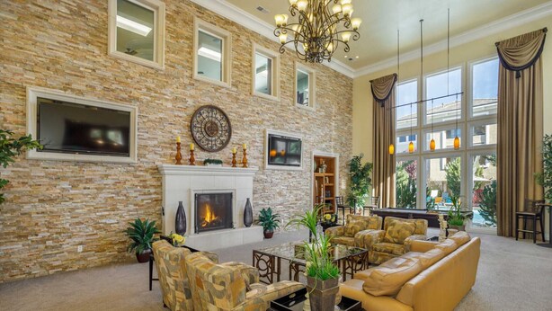 A spacious living room with a stone wall, fireplace, comfortable seating, and large windows. - New Elegant 1BR Retreat Heated Pool Gym Sauna (Reno)
