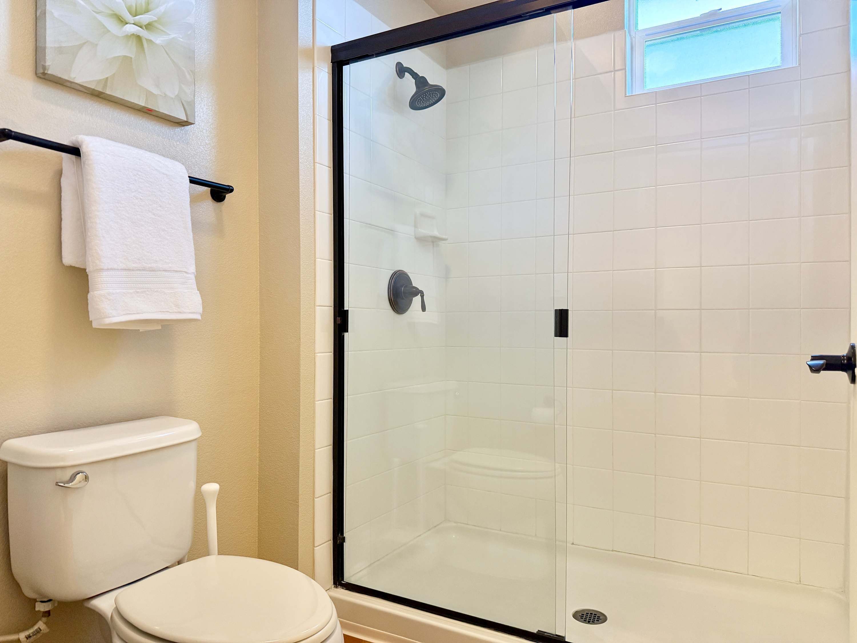 Un baño con ducha de vidrio, inodoro y perchero para toallas.