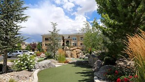 A residential area with a golf course, large rocks, and a building in the background.