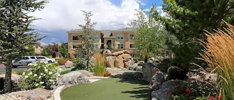 A residential area with a golf course, large rocks, and a building in the background.