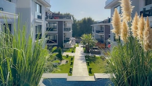 Un moderno complejo de apartamentos con un patio central, piscina y vistas del paisaje circundante.
