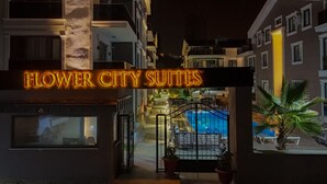 Entrada de un hotel con un letrero de neón que dice "Flower City Suites".