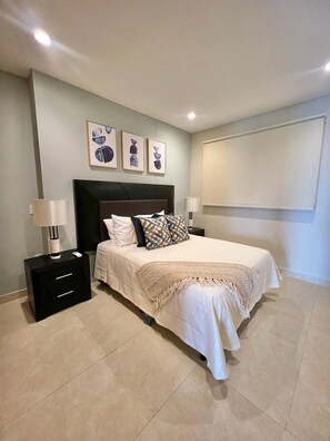 Relax in this serene bedroom with a large bed, nightstand, and abstract artwork.