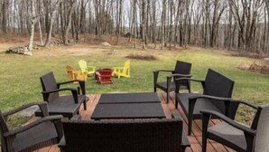 A deck with outdoor furniture, including chairs and a table, surrounded by a wooded area. - Spacious 4-bedroom house in fabulous Parksville perfect for Spring escape (Parksville)