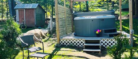 A backyard with a hot tub, wooden pergola, and a shed.