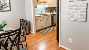 A modern kitchen with light-colored cabinets, a stainless steel refrigerator, and a dining area with a glass table and chairs. - Charming 2-Bedroom Townhome in Downtown Cary (Cary)
