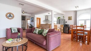 Una sala de estar moderna con un sofá morado, una mesa de centro de madera y un comedor con sillas de madera.
