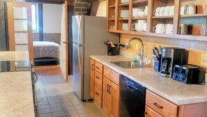 A compact kitchen with wooden cabinets, a dishwasher, a refrigerator, and a coffee maker. - Sam A Baker State Park (Patterson)