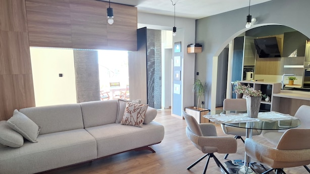 Una sala de estar moderna con un sofá, una mesa de comedor de vidrio y una mesa auxiliar.
