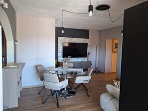 Un soggiorno moderno con una parete in marmo, un televisore a schermo piatto, un tavolino da caffè in vetro e mobili contemporanei.