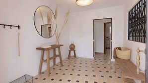 Un baño con piso de baldosas, un banco de madera, un espejo y un perchero para toallas.