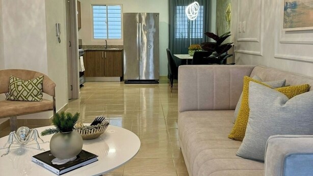 A modern living room with a round coffee table, a beige sofa, and a dining area with a table and chairs.