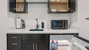 Una cocina compacta con armarios oscuros, un microondas y un refrigerador.