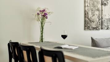 A dining table with chairs, a glass of red wine, and a vase with flowers.