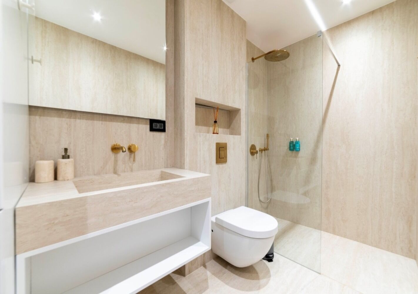 Un baño moderno con un tocador grande, inodoro y zona de ducha con mampara de vidrio.