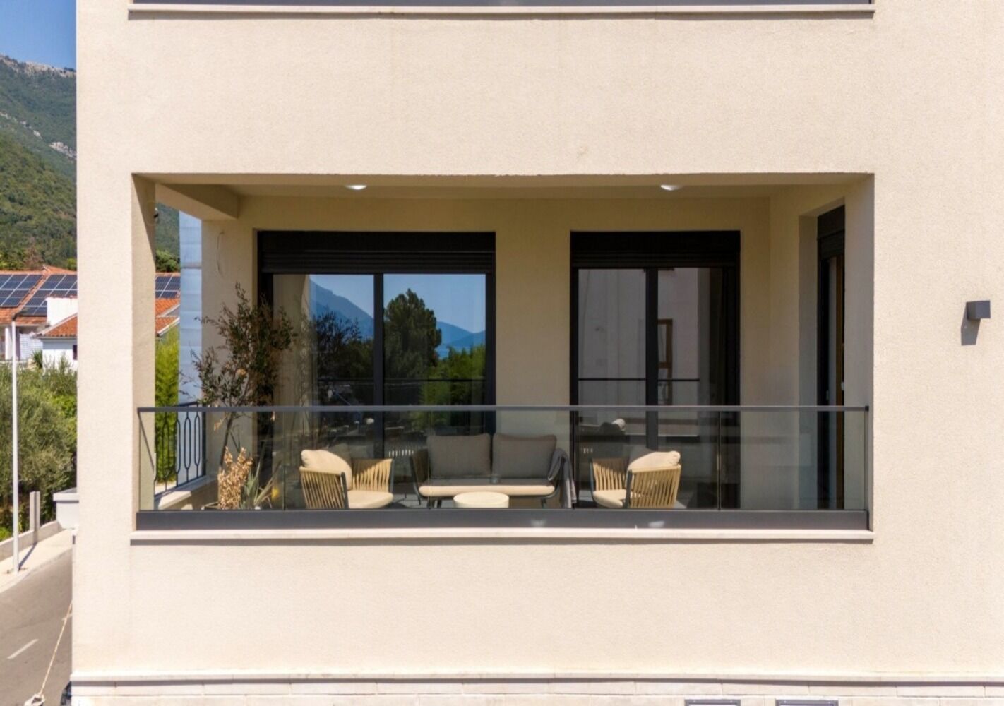 Un bâtiment moderne doté d’un balcon, d’un espace salon extérieur et de grandes fenêtres.