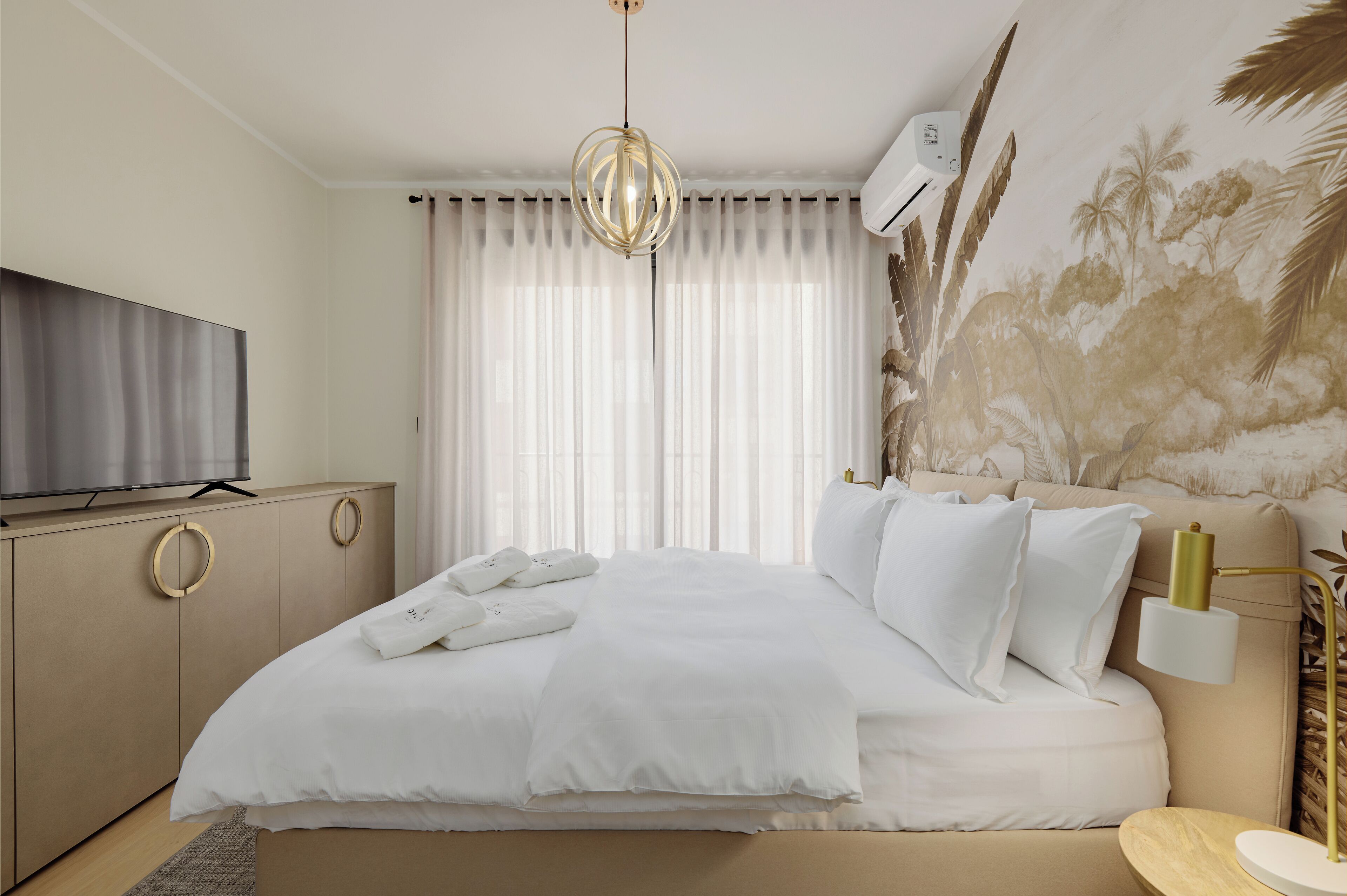 Een hotelkamer met een bed, een televisie, een kledingkast en een wandairconditioner.