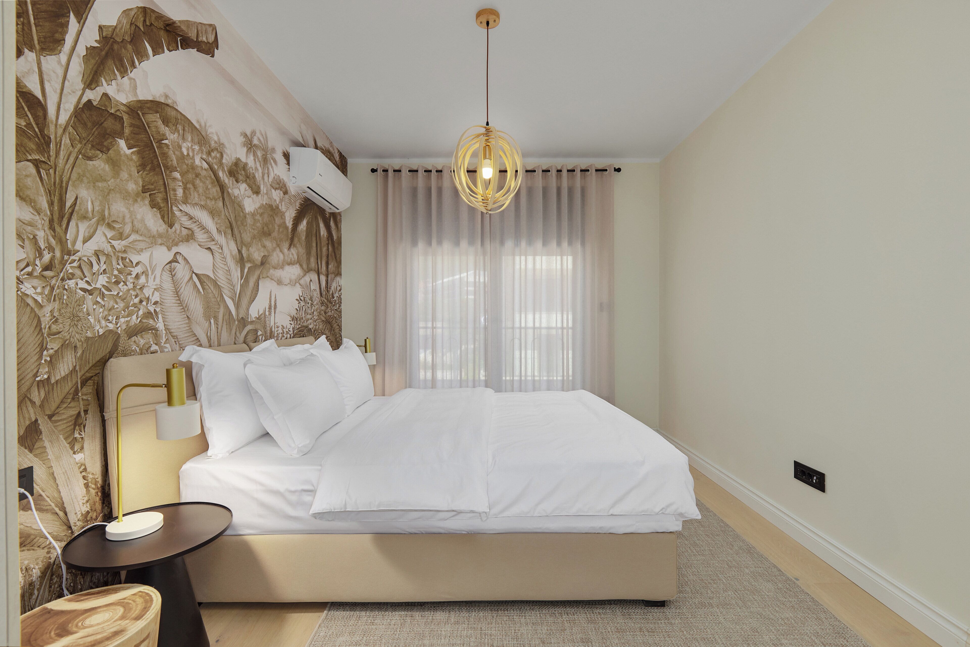 Un dormitorio con una cama grande, una mesita de noche, una lámpara y un aire acondicionado instalado en la pared.