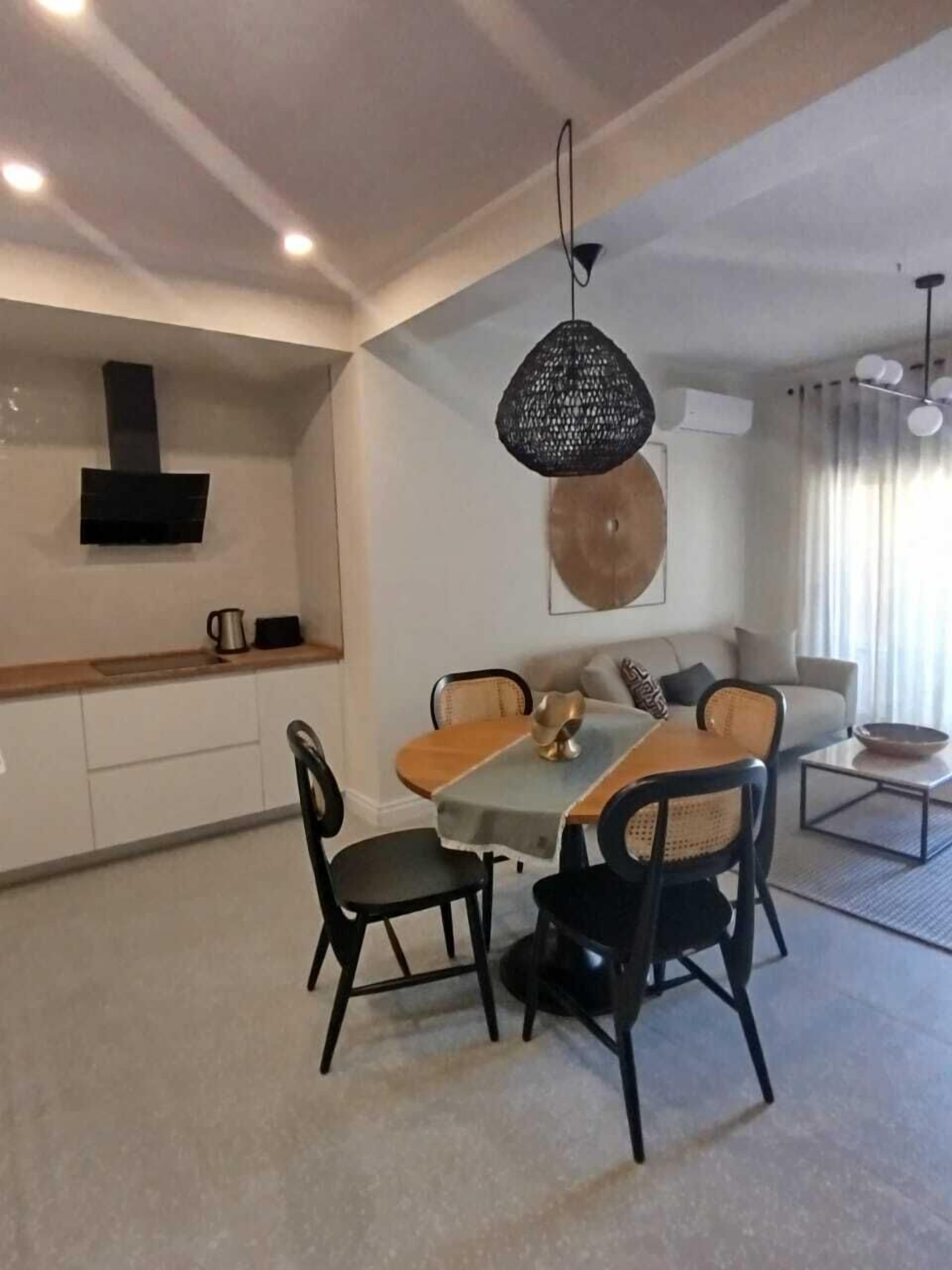 A modern kitchen with a built-in stove, a dining area with a table and chairs, and a living area with a sofa and a coffee table.