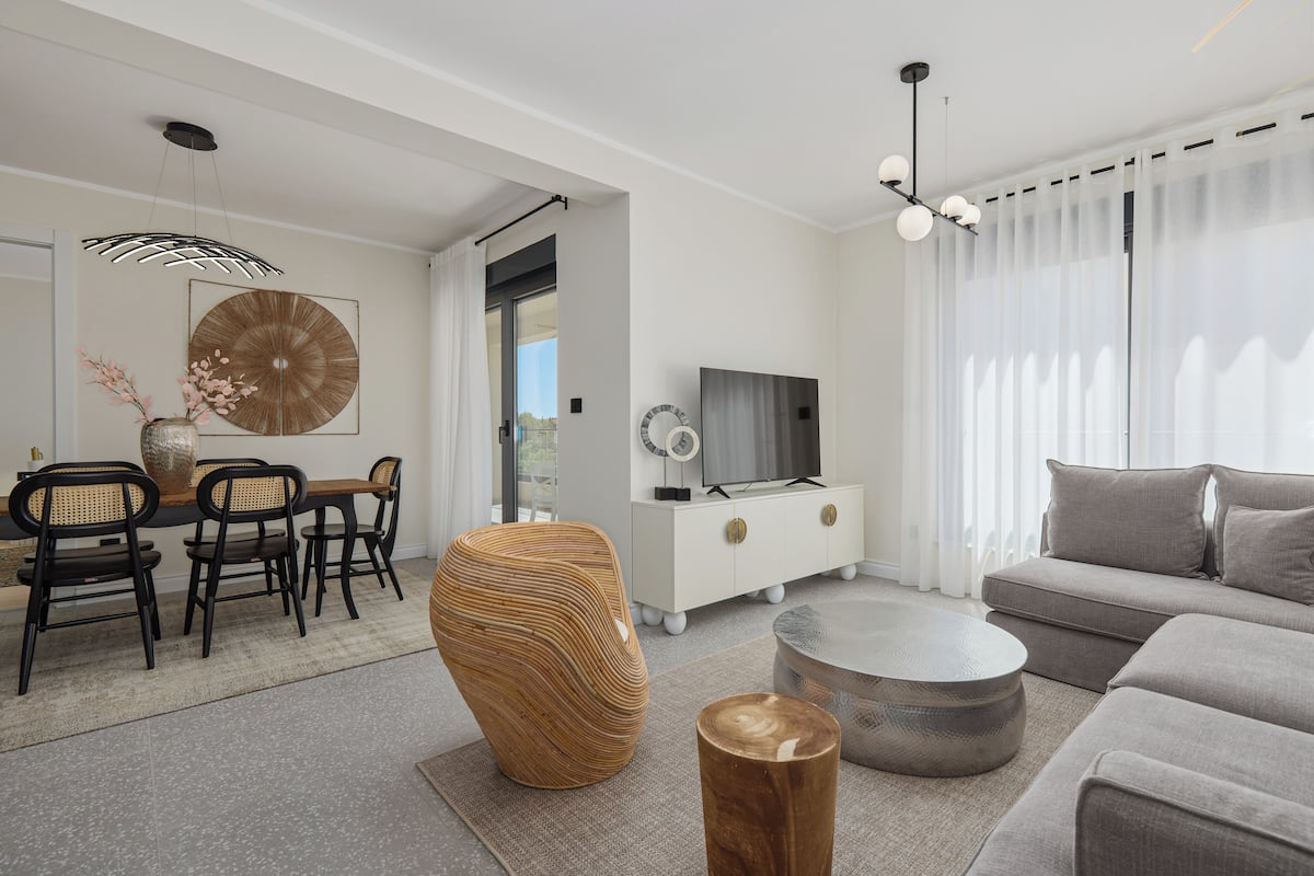 A modern living room with a dining area, a sofa, a TV, and a decorative vase.