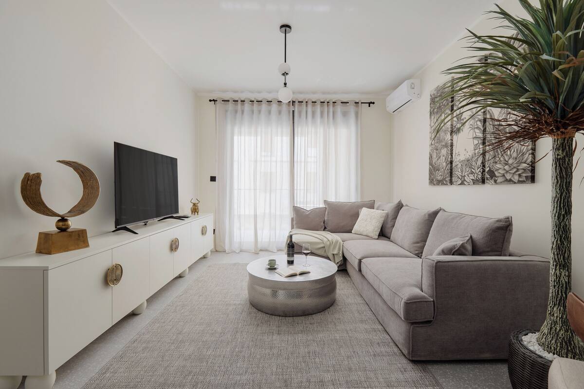A modern living room with a sofa, a coffee table, a TV, and a decorative piece on the sideboard.