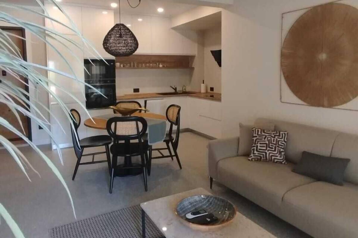 A modern living room with a sofa, coffee table, dining area, and kitchen.