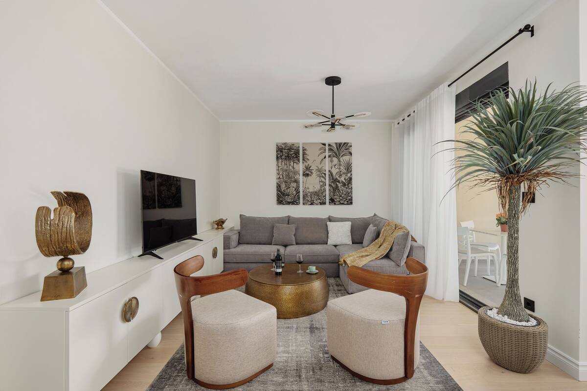 A modern living room with a sofa, two armchairs, a coffee table, and a TV.