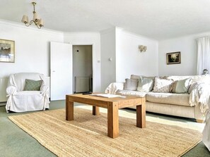 Un salon comprenant un canapé, un fauteuil, une table basse en bois et un tapis.