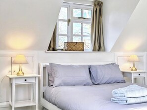 Une chambre à coucher avec un lit, deux tables de chevet, une fenêtre avec des rideaux et une lampe sur chaque table.