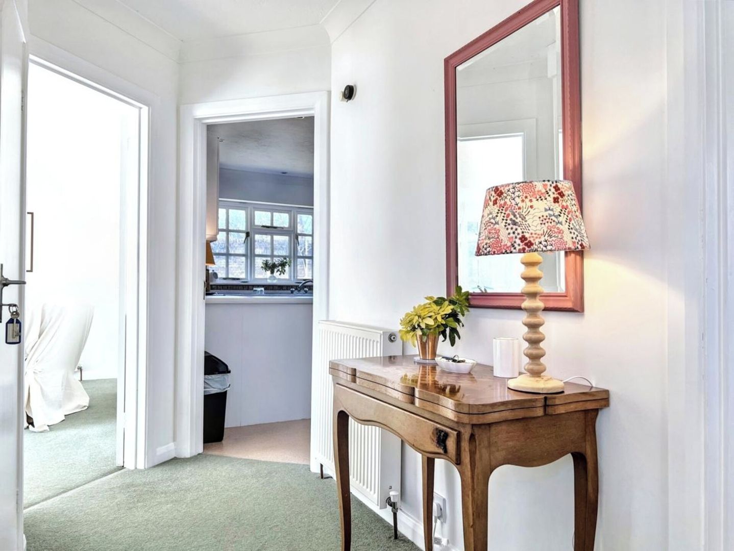Un couloir avec une console en bois, un miroir et un radiateur.
