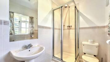 Une salle de bain avec une douche à parois de verre, un lavabo et des toilettes.