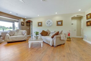 A living room with two beige sofas, a white coffee table, and a large wall clock.