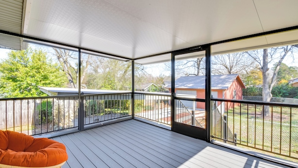 A covered deck with a wicker chair, large windows, and a view of a residential area. - 1 Mi to Dwtn Shops & Dining: Spacious Family Home (Hartwell)