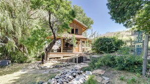 Een houten chalet met een veranda, omringd door bomen en een pad van stenen.