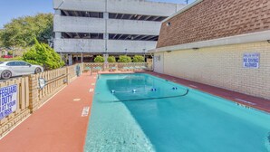 Una piscina con un muro de ladrillo y un edificio al fondo.