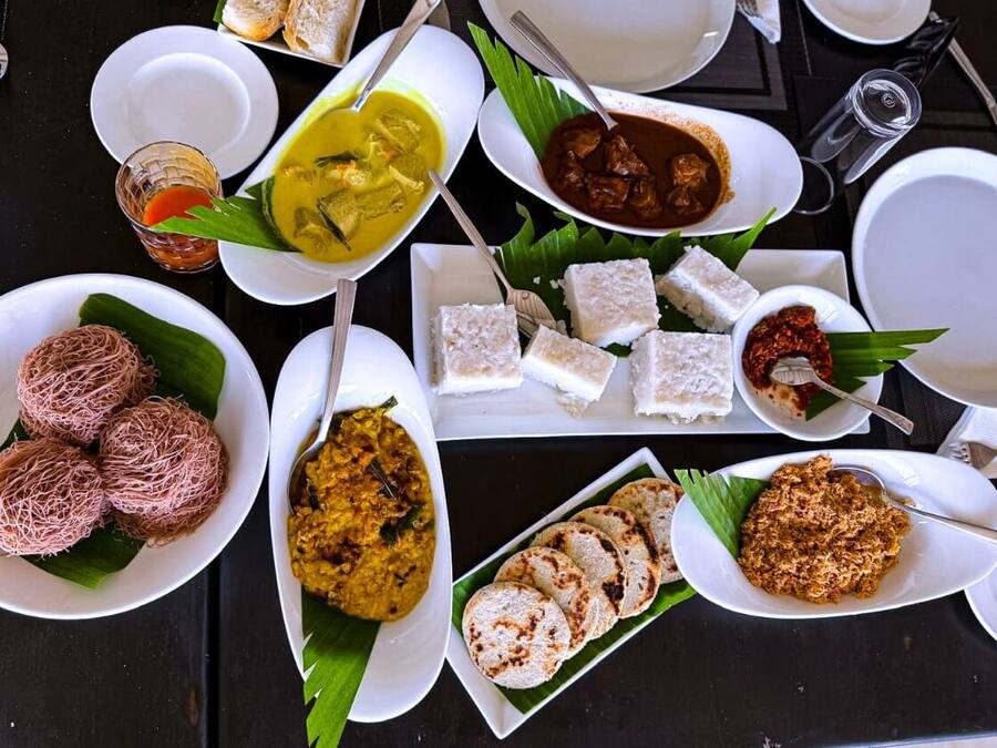 A table set with various dishes, including rice cakes, curry, and grilled items, suggesting a diverse meal selection.