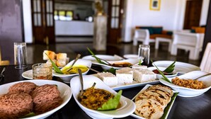 Een eettafel met diverse gerechten, waaronder platbrood, een curry en een dessert, in een moderne hotelsetting.