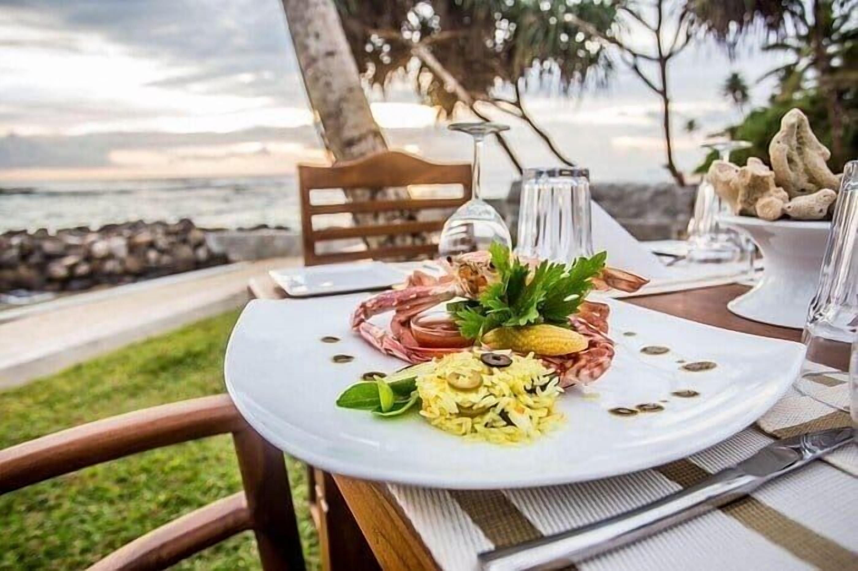 Une table à manger dressée avec une assiette de nourriture, un verre d’eau et un verre à vin.