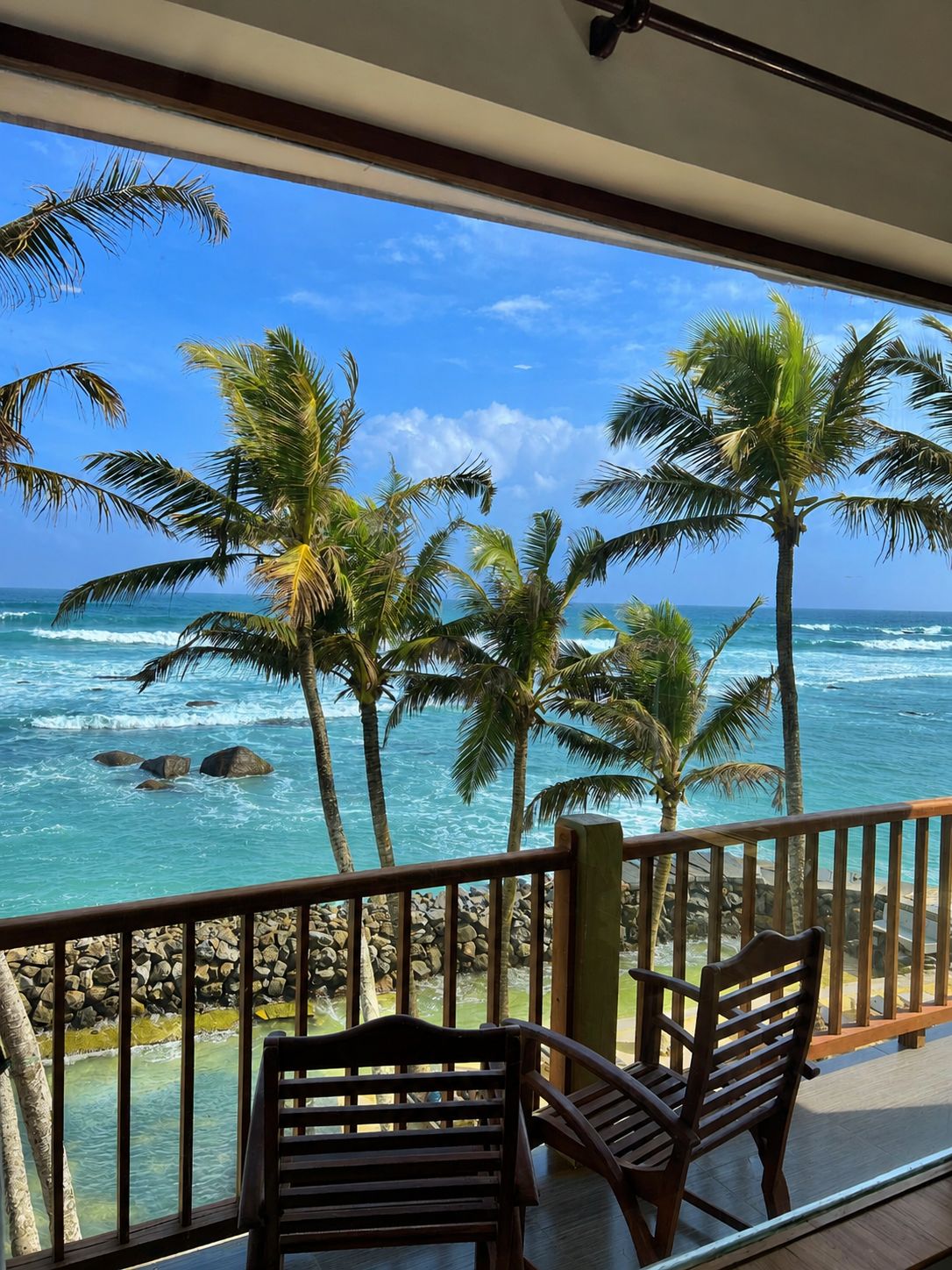 Un balcon avec vue sur l’océan et les palmiers.
