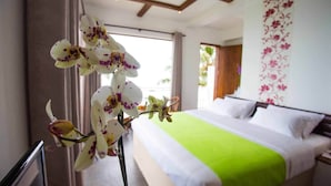 Een hotelkamer met een bed, een groene sprei en een potorkidee.